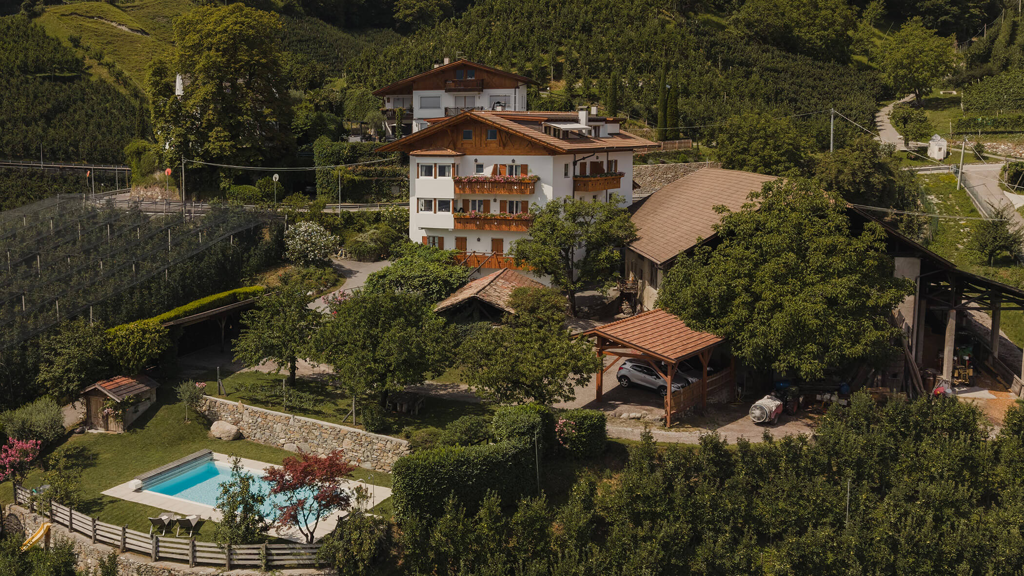 Luftaufnahme eines Landhauses mit Garten, Swimmingpool, Bäumen und Hügeln im Hintergrund. - Bucherhof