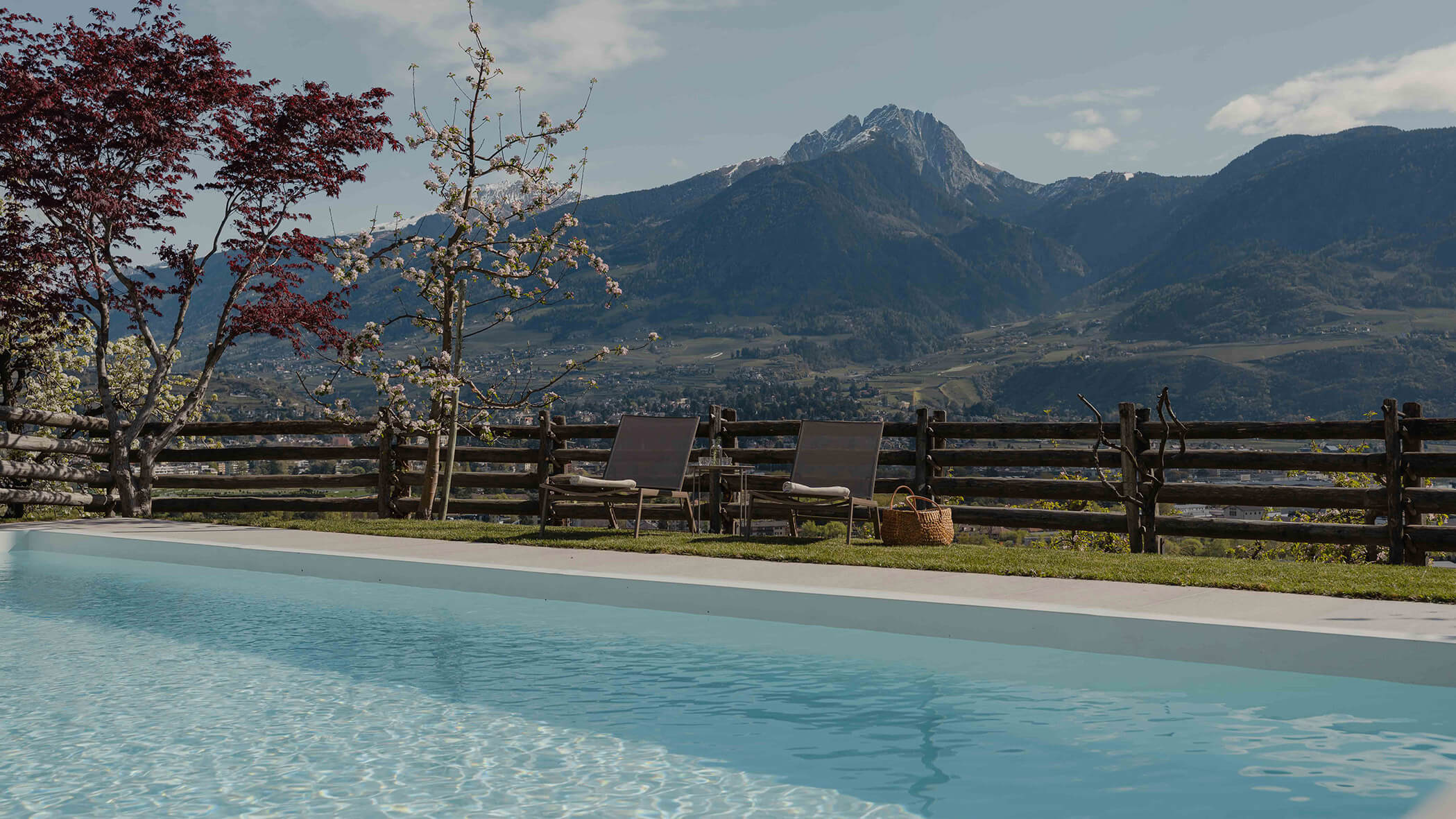 Ein Pool mit Liegestühlen und Bergen im Hintergrund an einem klaren Tag. - Bucherhof